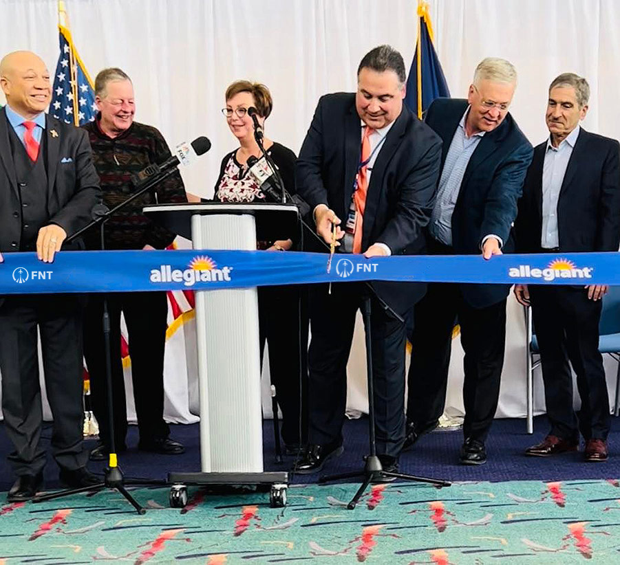 Six board members cutting an Allegiant airline ribbon. Pictured from left to right: Loyst Fletcher, Jr., Kevin Keane, Nino Sapone, A.A.E., Winfield Cooper, III, and Mark Yonan